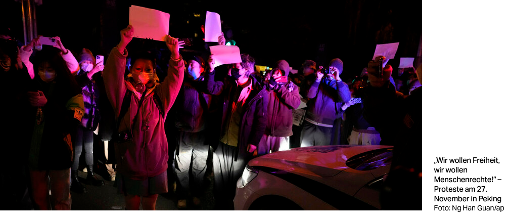 Group of protesting activists holding up blank posters, illuminated by colorful light.